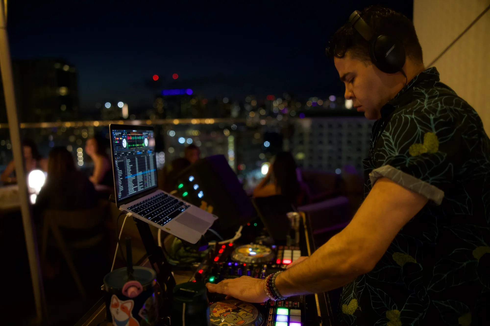 Billy Sage 5 at the DJ booth at dusk with the Honolulu skyline behind him