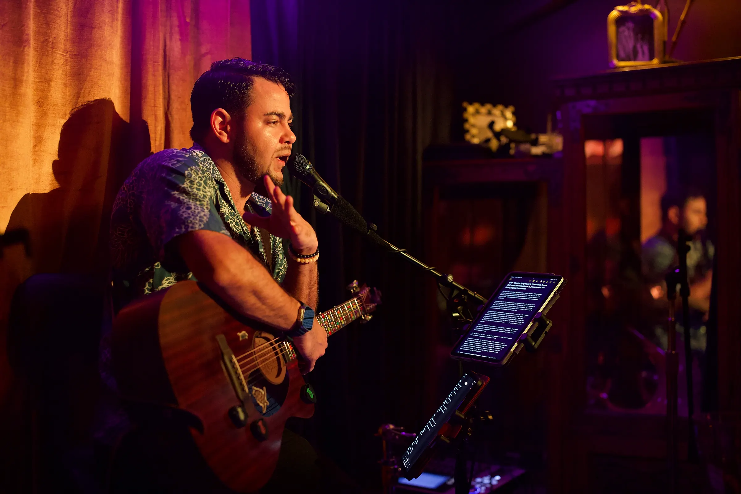 Billy Sage 5 singing and playing guitar under warm stage light at The Velvet Monkey in Honolulu